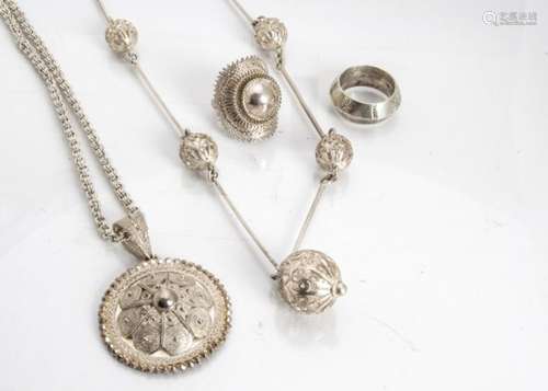 A collection of Ethiopian filigree white metal jewellery, including a roundel medallion, a sphere