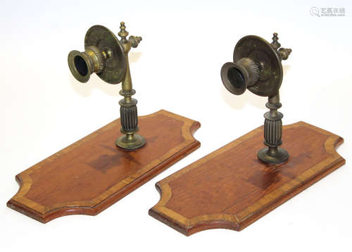 Pair of brass candlesticks on shaped wooden inlay bases, the bases 28cm long
