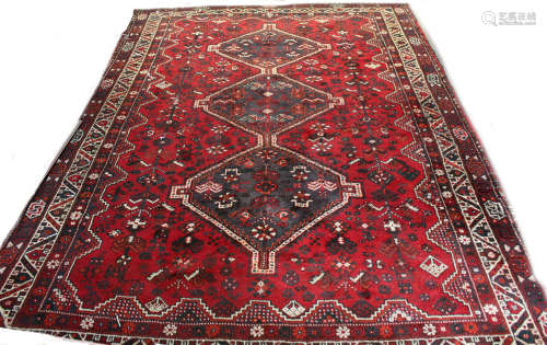 Iranian wool carpet, three lozenge centre within four gull border on mainly red field, 2.9m x 2.08m