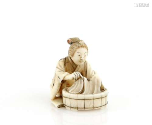 A stained ivory netsuke of a women beside a circular washing tub; signed on the base with two kanji,
