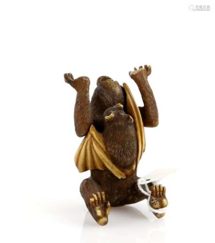 A heavily stained ivory okimono of a monkey, holding up both hands and being startled by a bat,