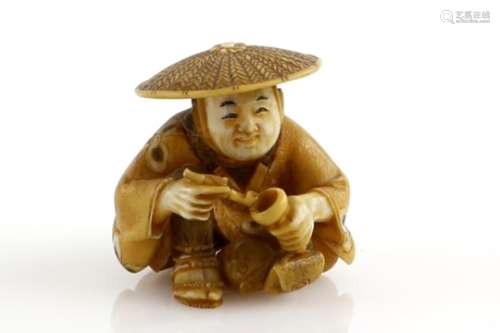 A stained ivory netsuke of a man, wearing a jingasa and holding a pipe with his right hand, signed
