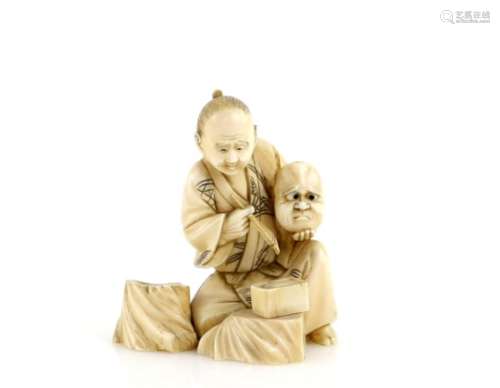 A slightly stained, sectional ivory okimono of a seated mask maker, 6.5 cm high, Meiji