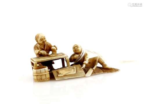 A small ivory okimono, or small netsuke with single himotoshi; carved as two men preparing food,