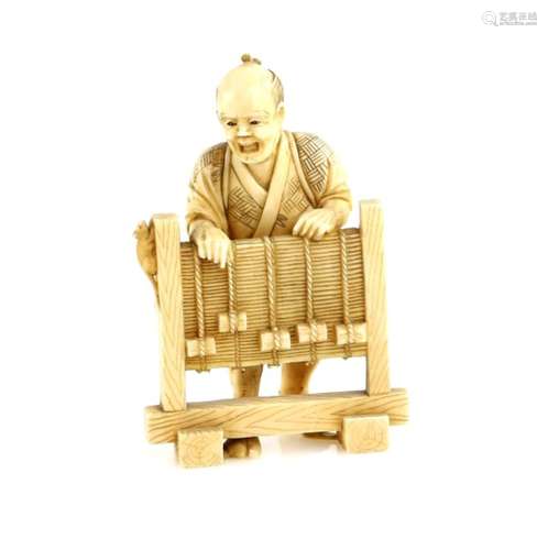 A stained ivory okimono of a Ratcatcher standing behind a screen, 9 cm high, Meiji PeriodProvenance: