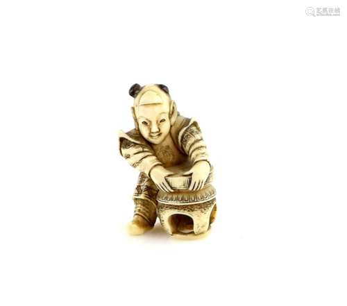 A stained ivory netsuke of a boy, lifting a stone from a table, 19th or 20th CenturyProvenance: