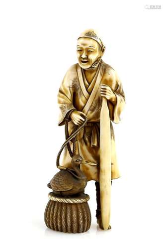 A stained ivory okimono carved as a cormorant fisherman with his bird beside him in a basket, 12