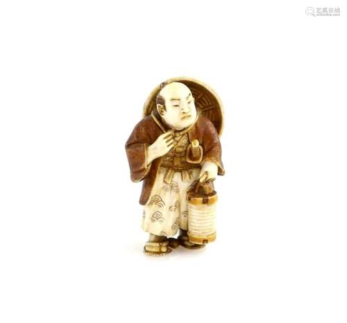 A stained ivory netsuke of a standing man with a jingasa on his back and a lantern in his left hand;