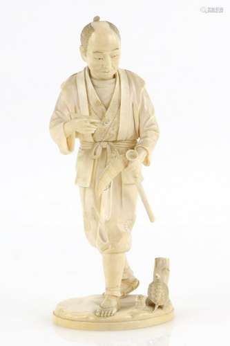 An ivory okimono carved as a standing man, holding a pipe with his right hand and with a scythe in