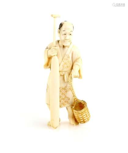 An ivory okimono of a standing boatman, holding a large oar beside a basket, 9.5 cm high, 20th