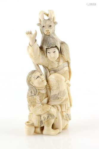 An ivory okimono carved as a seated hunter with a teppo beside a standing boy wearing a stag head