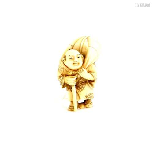 A stained ivory netsuke of a traveller wearing waraji, carrying a stick and holding a large sack