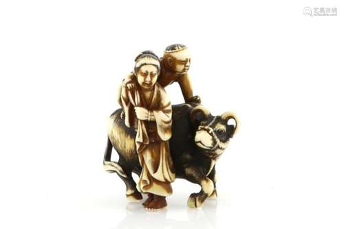 A heavily stained ivory netsuke, carved as a child on a water buffalo beside a standing women,