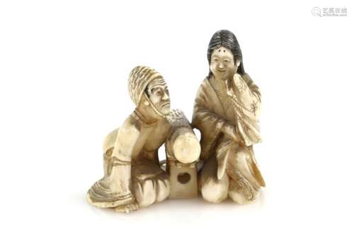 A stained ivory okimono of a man and women beside a large club, 5 cm high, 20th CenturyProvenance: