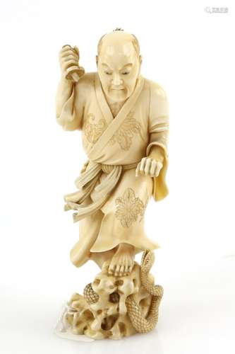 A stained ivory okimono, carved as a standing man killing a snake with a ko-wakizashi, 13 cm high,