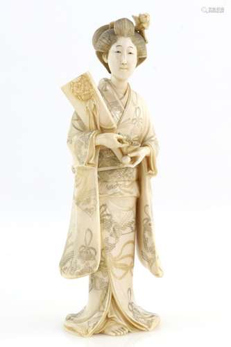 A stained ivory okimono, carved as a standing Yamato Nadeshko holding a hagoita racket in order to