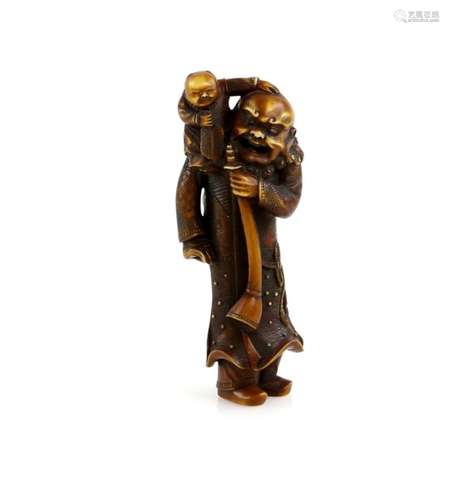 A heavily stained ivory netsuke carved as a Gaijin, holding a long horn with his left hand and