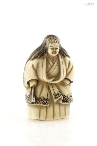 A stained ivory netsuke of a standing actor, holding a fan, in the role of a shojo; signed