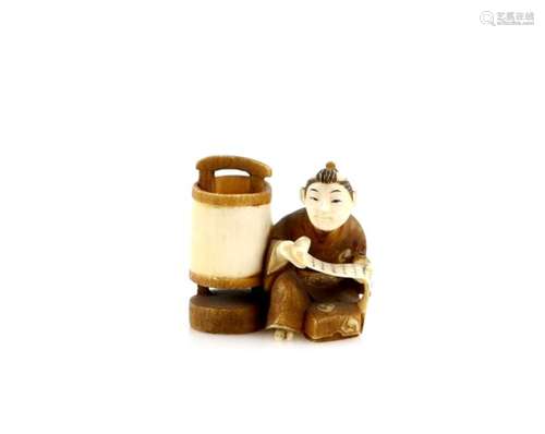 A stained ivory netsuke of a seated boy reading a makemono by lamplight, signed Kogyoku, 20th