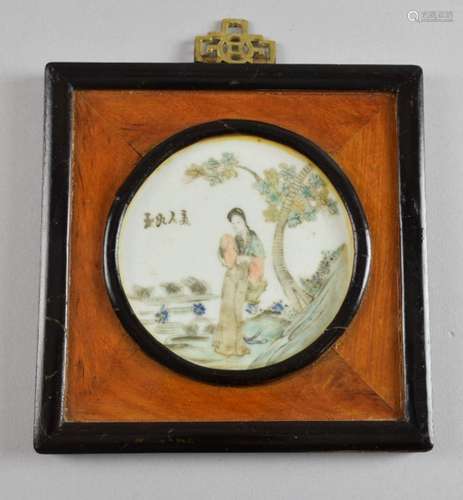 A Chinese porcelain, circular plaque decorated with a lady in a garden beside four characters, 9.7cm