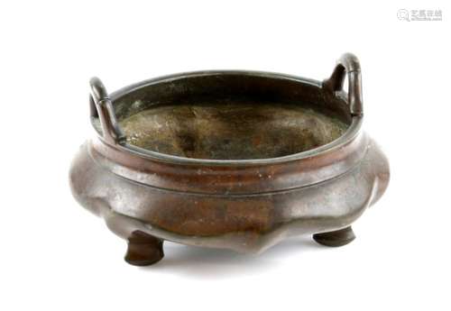 A Chinese metal alloy incense burner on tripod feet; with looped handles and undulating design on