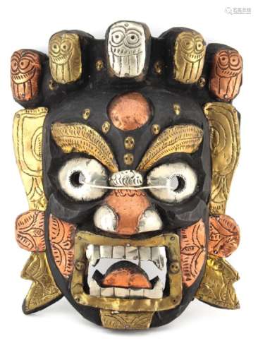 Property of a gentleman - a carved wood, tin, copper & brass clad Mahakala mask, 11.8ins. (30cms.)