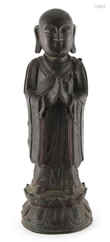 A Chinese bronze figure of Buddha, Ming Dynasty (1368-1644), modelled standing in prayer, on