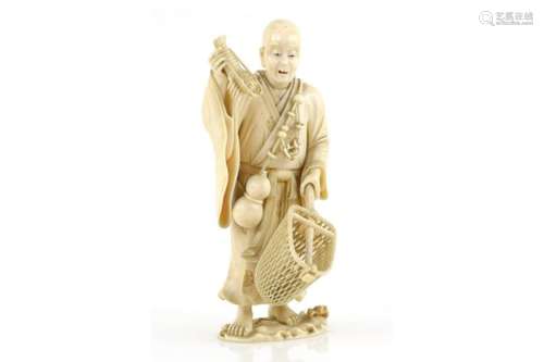 An ivory okimono carved as a standing lobster fisherman, holding a crustacean in his right hand