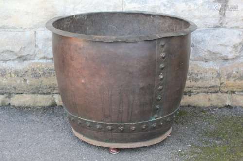 A Vintage Copper Fireside Log Storage Bin; the unit measures approx 68 cms dia, decorative band with studs near the base, wood base on bun feet
