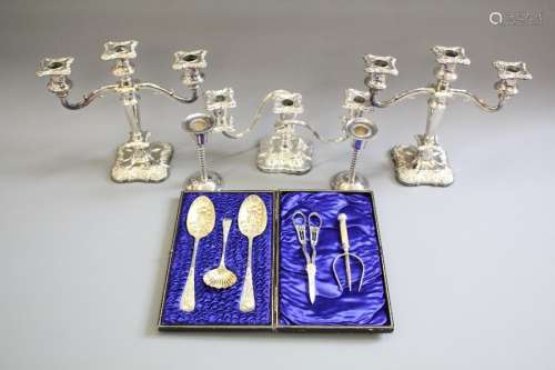 A Collection of Silver Plate; the lot includes silver spoon, meat fork, grape scissors, a pair of berry spoons (in presentation box), boxed sugar spoon, two three-branch candle holders, approx 25 cms h, two single candle holders approx 14 cms h, and one three-branch candlestick holder approx 15 cms h