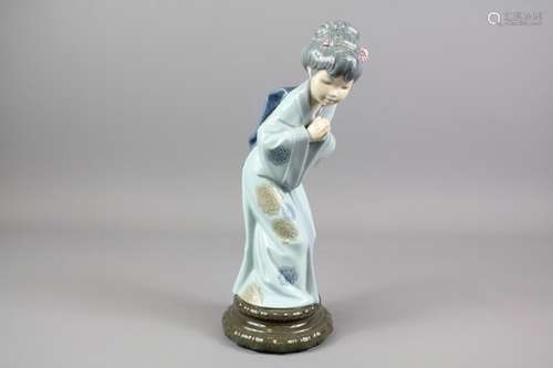 Lladro Figurine of a Japanese Geisha; the figure bowing with her hands clasped together, with blossoms in her hair, approx 28 cms h, presented in the original box