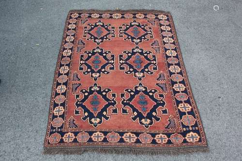 An Afghan Wool Carpet; the carpet having a Russet and Navy ground with paler blue in the central medallions approx 205 x 145 cms, tassels and selvedges complete