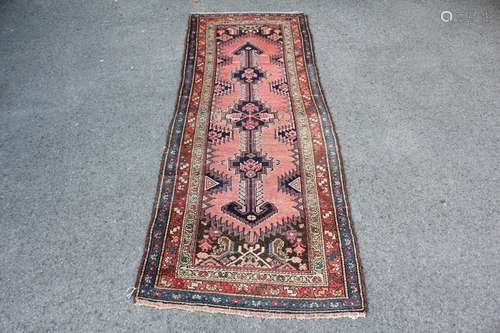 Antique Persian Wool Runner Carpet, having a Salmon pink ground with Navy and Red geometric patterns, approx 275 x 105 cms, selvedges and tassels complete