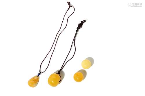 A GROUP OF THREE MODERN AMBER PENDANTS.