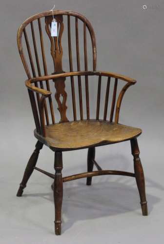 A mid-19th century yew and elm Windsor armchair, the pierced splat and spindle back above a solid