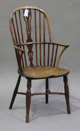 A mid-19th century yew and elm Windsor armchair, the pierced splat and spindle back above a solid