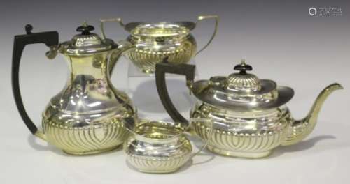 An Edwardian silver four-piece tea set of half-reeded form, comprising hot water jug, teapot, two-