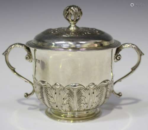 A George V silver two-handled cup and domed cover with foliate finial, decorated in relief with