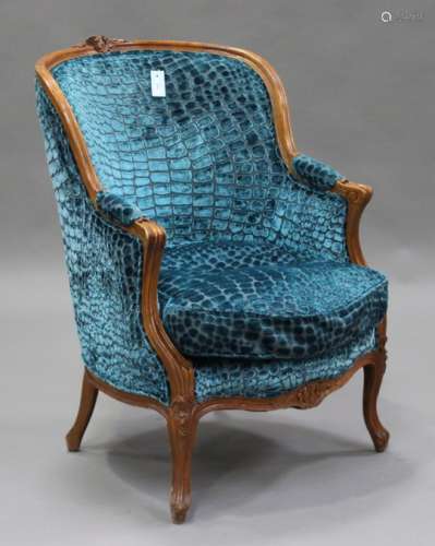 A 20th century Louis XV style walnut fauteuil armchair with carved decoration, upholstered in