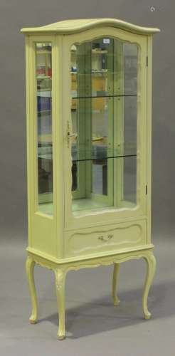 A late 20th century white painted vitrine, fitted with a glazed door and a drawer, on cabriole legs,