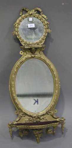 A late Victorian gilt composition oval wall mirror with a circular mirror surmount and shelf