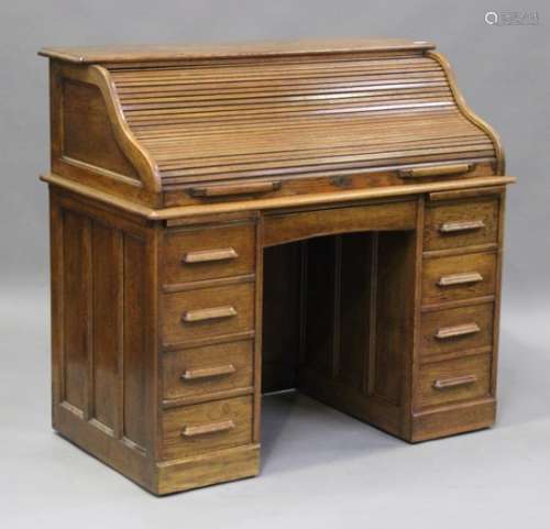 A George V oak roll-top desk, the serpentine tambour shutter enclosing a fitted interior above