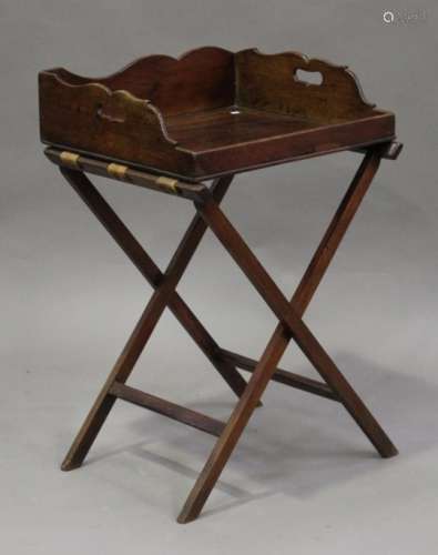 A George III mahogany butler's tray and folding stand, the shaped gallery with pierced handles,