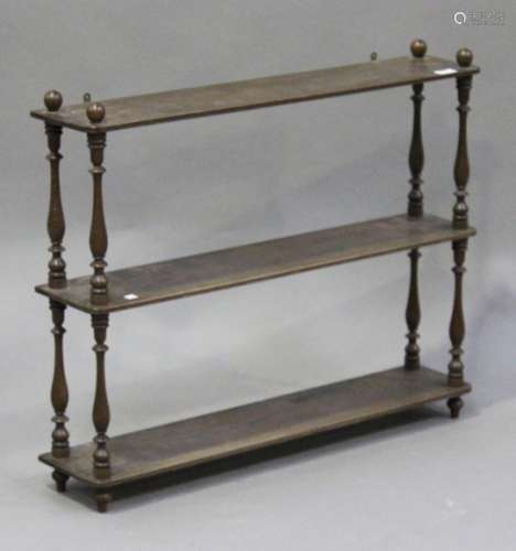 A late 19th/early 20th century limed mahogany three-tier hanging wall shelf with ball finials and