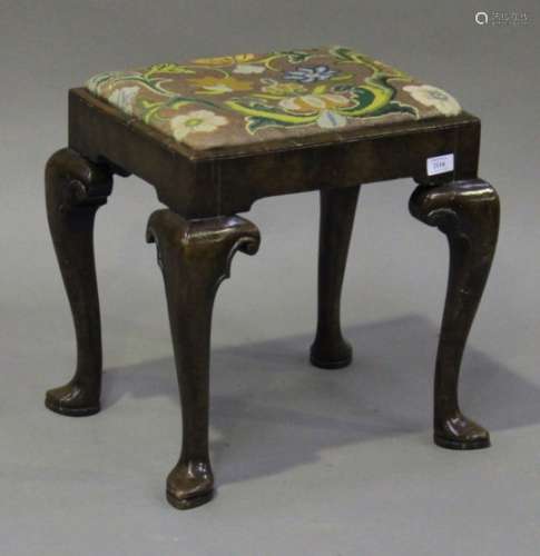 An early 20th century George I style walnut stool, the needlework drop-in seat raised on carved