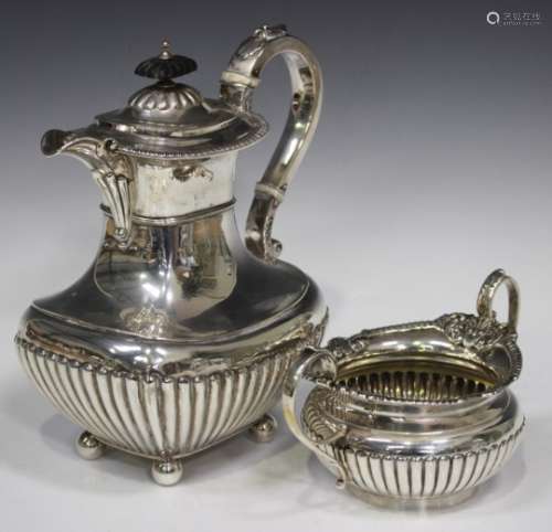 An Edwardian silver half-reeded hot water pot of cushion form with gadrooned rim, on ball feet,