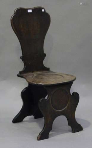 An early George III mahogany hall chair, the shaped back above a dished solid seat, on shaped