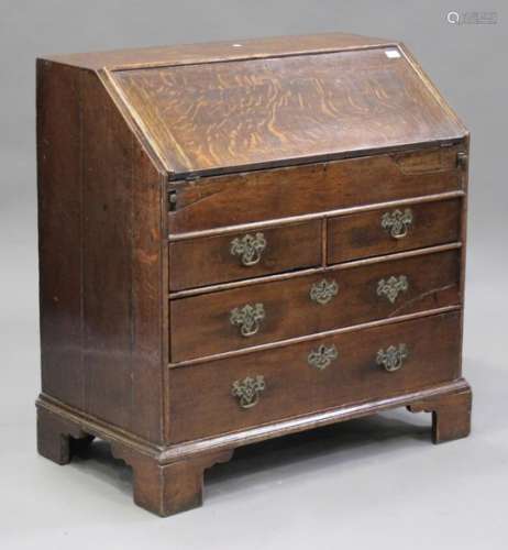 A George II oak bureau, the fall flap enclosing drawers, pigeonholes and a well above two short