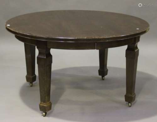 A George V mahogany circular extending dining table, raised on square tapering legs and castors,