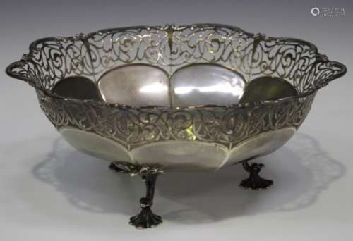 An Edwardian silver circular fruit bowl, the rim with pierced scrollwork decoration, on three leaf